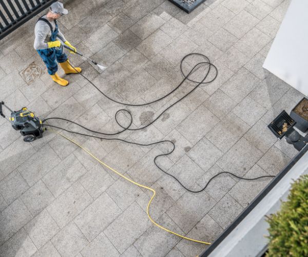 Aerial view of pressure washing professional cleaning a stamped concrete driveway